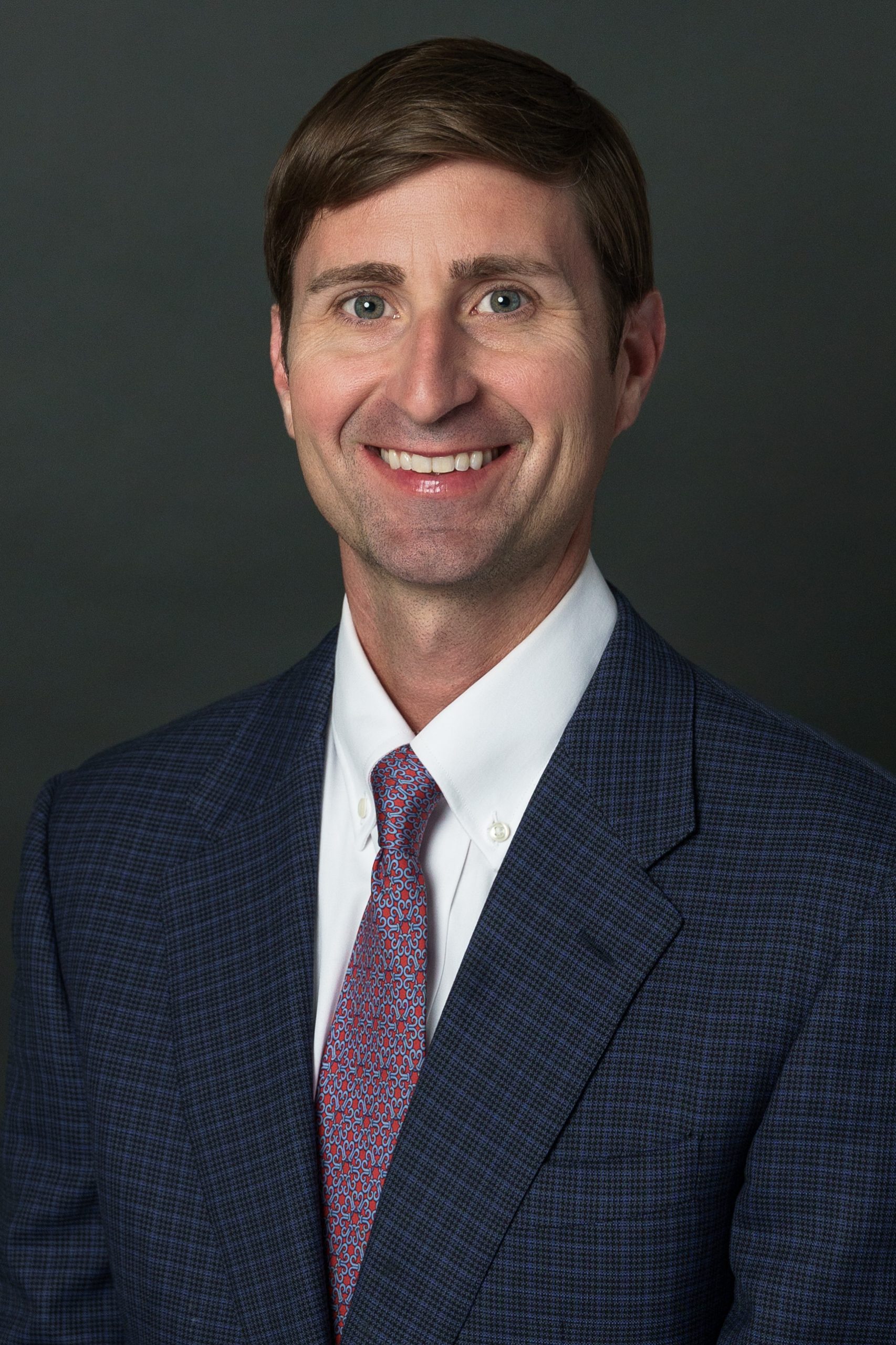 a man wearing a suit and tie smiling at the camera